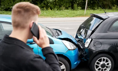 A driver on the phone calling for help after a read-end collision by a rideshare driver.