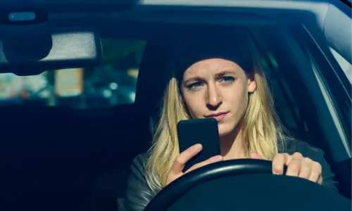 A blonde driver talking on her phone while driving her vehicle.