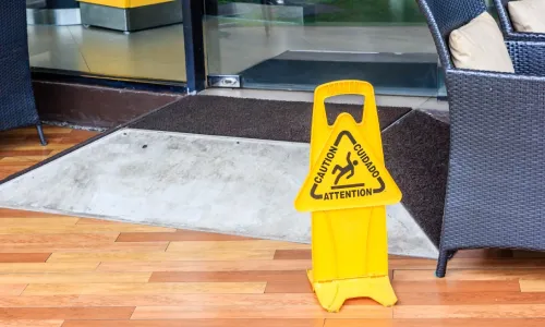 A caution sign on the floor of a cafe warning of potential slips and falls.